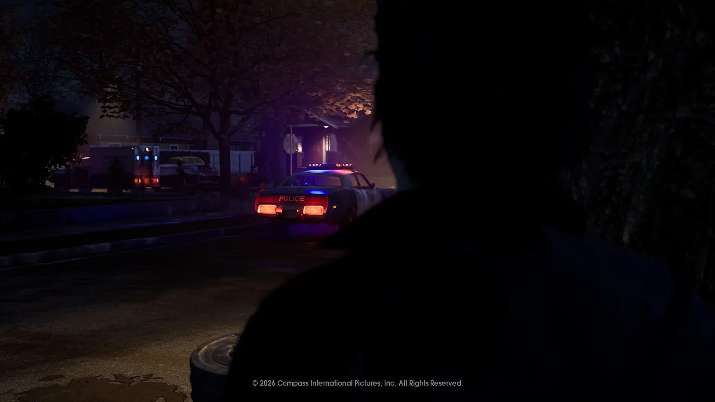 Michael Myers stands in shadow while police gather on a Haddonfield street at night.